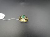 Gros plan sur une bague en or ornée d'une pierre verte