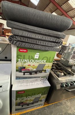 a stack of sunloungerr and a washing machine in a store