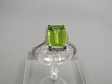 gros plan d'une bague avec une pierre verte entourée de diamants