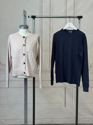 three sweaters on a mannequin stand in front of a white wall
