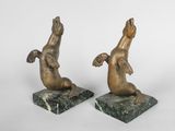 paire de sculptures en bronze représentant un chien et un chat, posées sur des socles en marbre