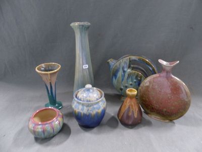 de nombreux vases de formes variées posés sur une table, sur fond gris