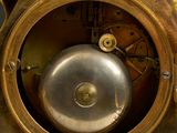 a gold clock with a metal bell on top of it