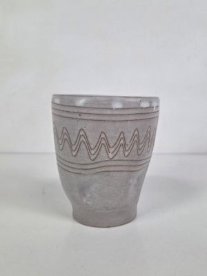 a gray cup that has a wavy design on it