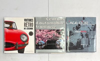 trois livres posés sur un mur blanc, avec une voiture rouge et une voiture noire