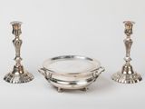 two silver candlesticks and a bowl on a white background
