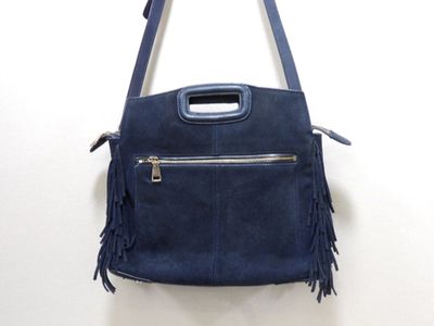 blue sued purse with fringes hanging on a wall