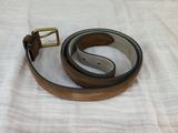 brown leather belt with a brass buckle on a white background