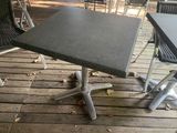 une table et des chaises noires sur une terrasse en bois