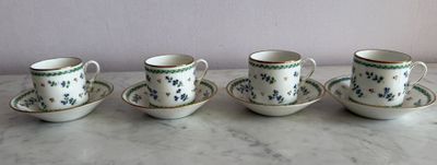 four cups and saucers are lined up on a marble table