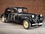a old black car parked in front of a brick wall