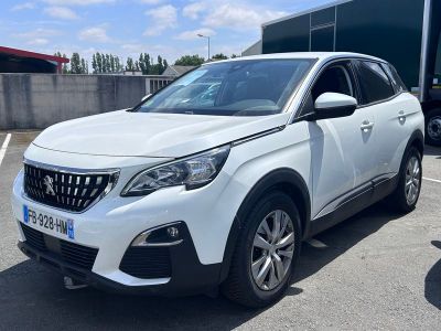 La voiture blanche est garée sur le parking, à côté du camion.