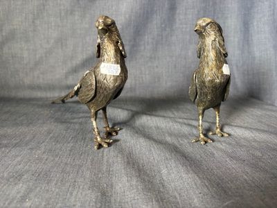 pair of silver colored metal birds on a gray background