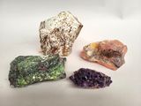 trois types différents de roches et de cristaux sur une surface blanche