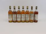 six bouteilles de whisky alignées sur une surface blanche