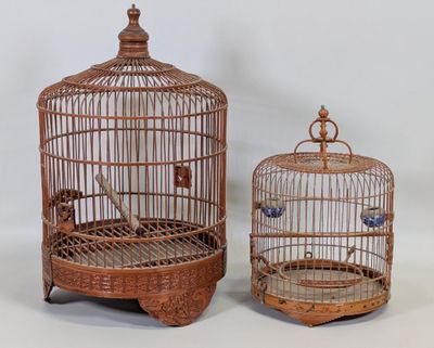 une paire de cages à oiseaux anciennes contenant des oiseaux, posées sur une surface blanche