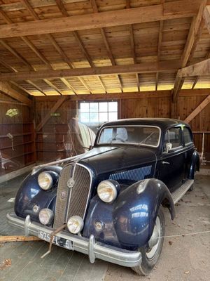 une vieille voiture bleue dans un garage au plafond en bois