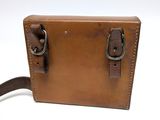 brown leather bag with two handles and a strap on a white background