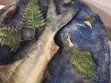 a fish that is sitting on a plate with leaves