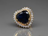 a close up of a ring with a blue stone surrounded by white diamonds