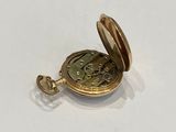 a small gold pocket watch on a white surface