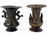 two bronze vases sitting side by side on a white surface