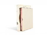 un vieux livre à la couverture rose posé sur une surface blanche