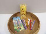a wooden bowl with pens, pencils, and a box of crayons on it
