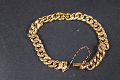 gros plan d'un bracelet en chaîne en or sur une surface noire