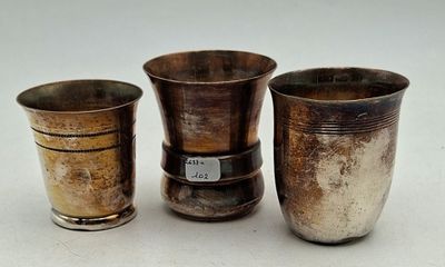three silver vases sitting next to each other on a white surface
