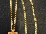 a gold necklace with a square pendant on a chain