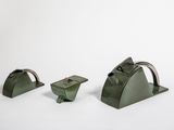trois morceaux de métal vert posés sur une surface blanche, sur fond blanc