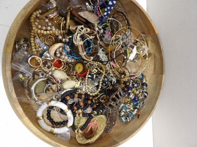 un bol en bois rempli de bijoux variés, posé sur une table