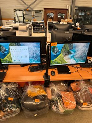 two computer monitors sitting on top of a wooden desk