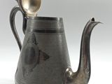 a silver tea pot with a spoon in it