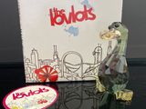 une figurine en verre représentant un oiseau, posée sur une table à côté d'une boîte