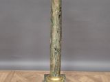 une horloge ancienne en bronze posée sur un socle, sur un parquet