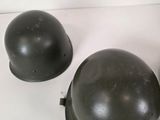 two army helmets sitting on top of a table next to each other