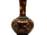 un vase rouge orné de motifs dorés sur fond blanc