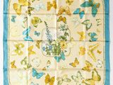 un foulard carré bleu et jaune orné de papillons et de fleurs