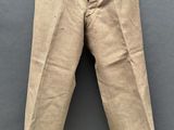 un gros plan sur un pantalon beige posé sur une surface grise