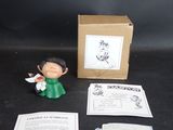 une petite figurine représentant un homme en robe verte, à côté d'une boîte
