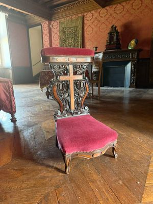 une chaise au milieu d'une pièce, avec un lit à l'arrière-plan
