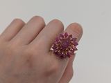 quelqu'un tient dans sa main une bague en forme de fleur violette