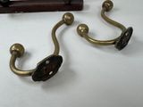two brass hooks on a white table next to a clock