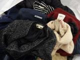a pile of clothes sitting on a bed with a tag on it