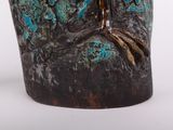 a close up of a vase with a bird on it ' s head