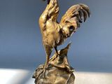 a statue of a rooster sitting on top of a rock