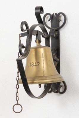 une cloche accrochée au mur, entourée d'une chaîne