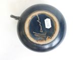 a blue vase with a black handle on a white surface